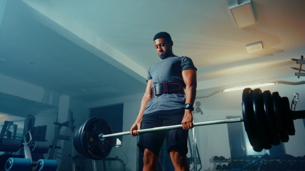 Strong muscular man performing deadlift exercise in a modern gym.